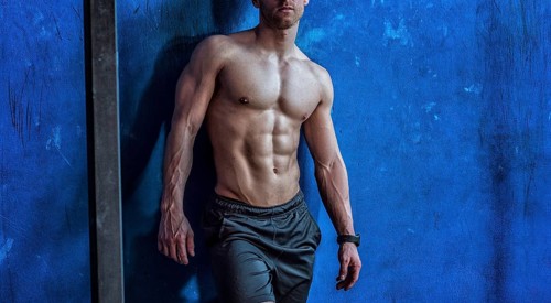 Attractive and muscular shirtless young man leaning against wall in gym, to rest or relax after