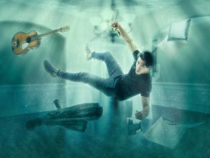Illusion of man floating underwater among objects in room looking at camera
