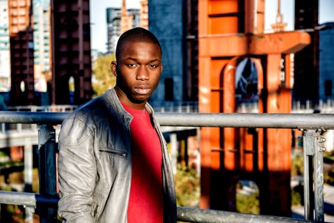 Portrait of a sexy young black man in urban environment wearing red shirt and grey leather jacket