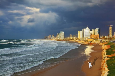Storm cloud hanging over the sea, the woman in white performs yoga on one leg. Promenade and beach