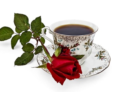 Coffee in a cup with a pattern of roses and flower red rose isolated on white background