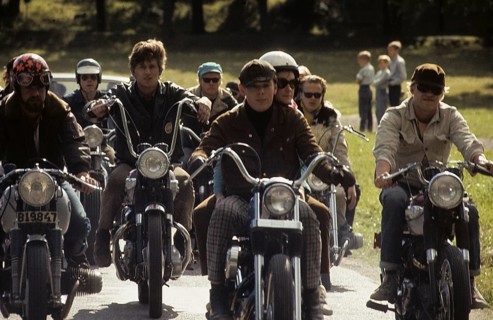 In the 1960s. Motorcyclists on the road together. Cool and trendy looking riding thir bikes. The