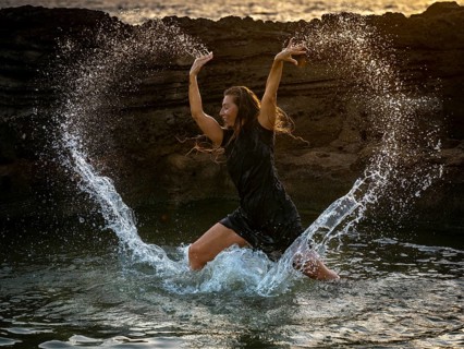 Middle-aged woman dancing and throwing water in the air, Maioris beach, llucmajor, Majorca,
