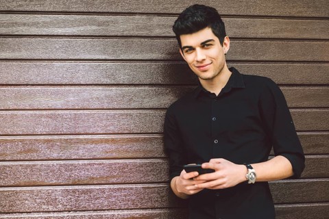 Portrait of young handsome Turkish male model. Mediterranean race brunette in black shirt is using