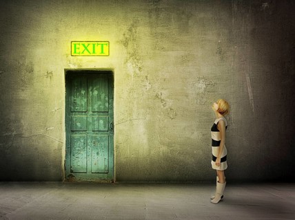 Young woman in black and white dress stand in front of blue door in dark grungy room watch on