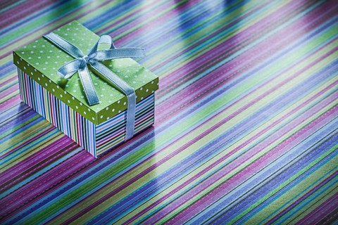 Cardboard present box with ribbon on striped tablecloth celebrations concept