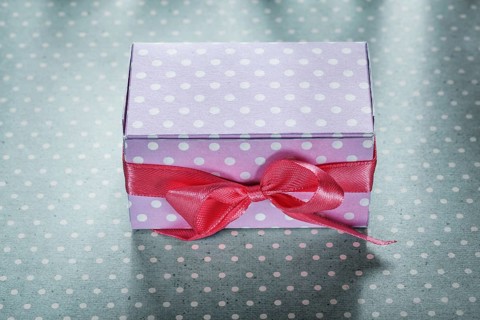 Pink present box on blue polka-dot tablecloth holidays concept