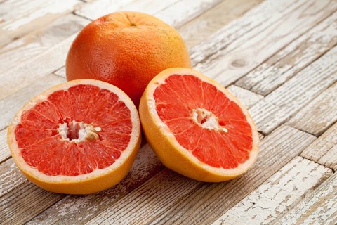 Red cut grapefruit on white grunge wood table with paint peeling off