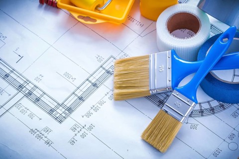 Blueprint with paint roller tray brushes bottle duct tape and wooden meter copy space image
