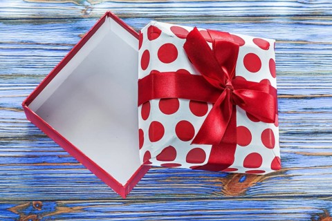 Opened gift box with bow on vintage wooden board