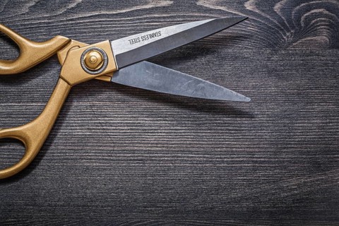 Pair of golden scissors on vintage wooden board top view