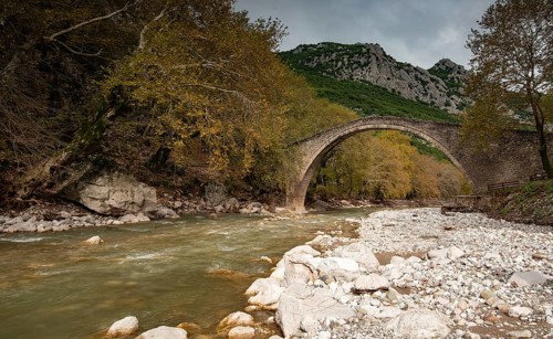Ancient, stoned, arched bridge St. Vissarion on the Portaikos river in autumn. Trikalla pyli