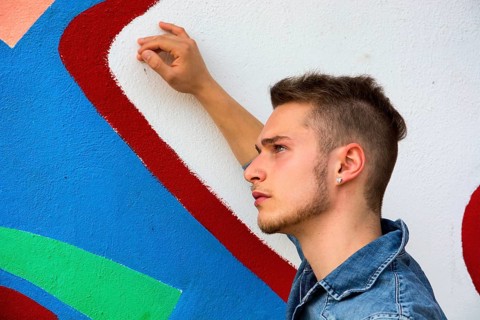 Attractive young blond man against colorful graffiti wall, wearing denim shirt