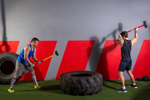 Sledgehammer Tire Hits men workout at gym with hammer and tractor tire