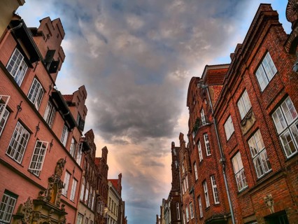 Historic red brick buildings under a dramatic cloudy sky, gothmund, travemünde, lübeck, germany