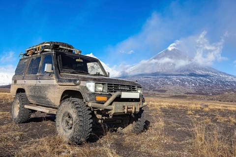 Lifted sport utility vehicle Toyota Land Cruiser Prado on background eruption active Klyuchevskoy