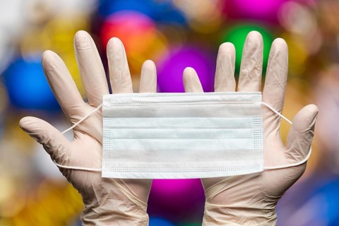 Doctor hands holding medical face mask in white gloves on background bokeh Happy New Years balls