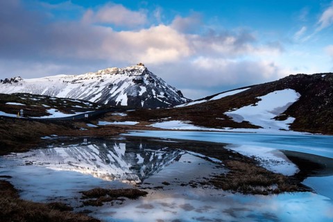 Icelandic landscape with frozen lake and stapafell mountains covered in snow and reflected on water
