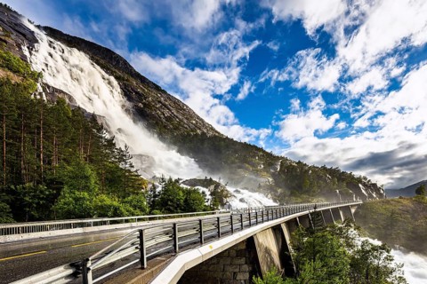Huge powerful and roaring cascading Langfossen waterfall on the Vaule river. The bridge is fenced