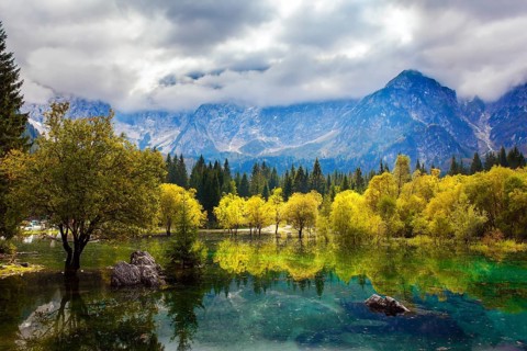 The Dolomites are covered with clouds. Lake Fuzine in Northern Italy. Magnificent colors of autumn.