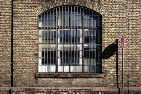 A no stopping sign casts a shadow on the brick wall on the disused industrial site of an old