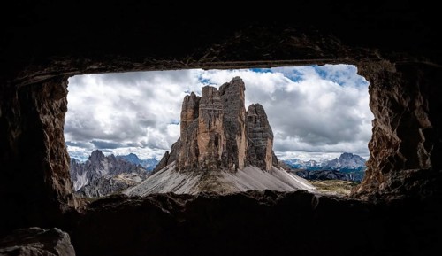 View out of an old military tunnel window towards the iconic Three Peaks mountain in the Dolomite