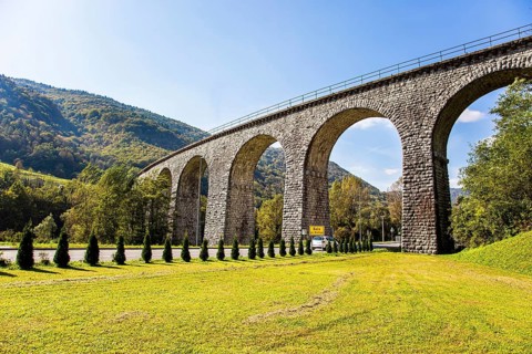 Picturesque Julian Alps. Beautiful sunny autumn day. Majestic powerful bridge over the river Idrija
