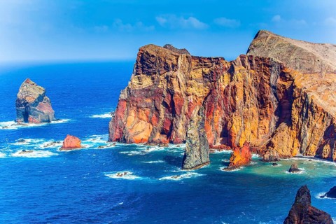 The west coast of the island of Madeira - red rocks, turquoise surf. The blinding midday sun