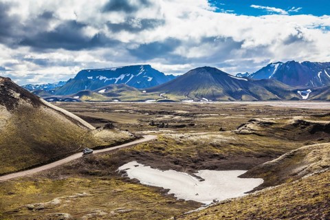Summer trip to Iceland. The dirt road in a valley surrounded by mountains
