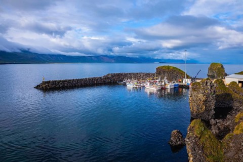 White fishing boat in the harbor pier fishing village Arnastapi. Sunset on the sea fjord in Iceland
