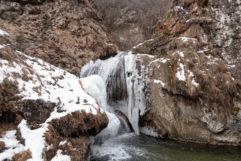 The waterfalls, which are not completely frozen in winter, flow down from the porous rocks