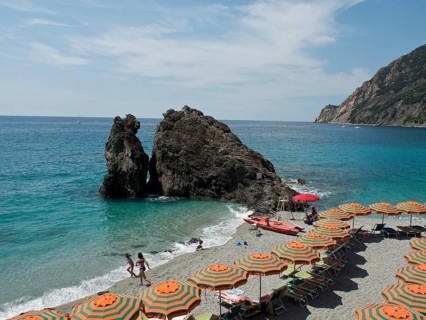 Beach with orange-green parasols, turquoise sea and rocks, Monte rosso, cinque terre, Italy, Europe