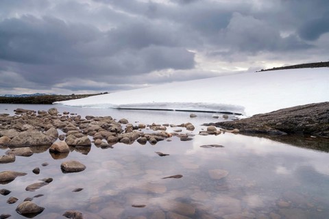 Heavily clouded sky reflecting in a lake on the Norwegian mountain plateau Aurlandsfjellet