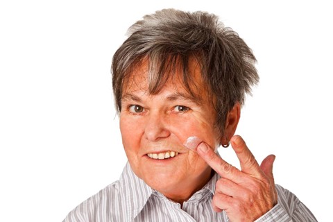 Senior woman with cream pot cropped on white background