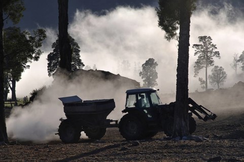 Tractor spreading lime with a fertiliser spreader, West Coast, New Zealand, Oceania