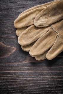 Pair of leather working gloves on vintage wooden board close up view construction concept