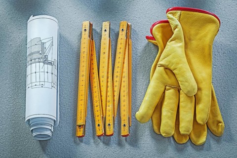 Leather protective gloves construction plans wooden meter on concrete background building concept