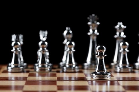 Steel chess figures standing on wooden chessboard. Intellectual duel and tactical battle in