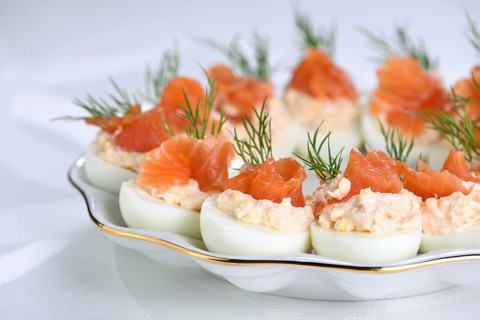 Appetizer of stuffed eggs stuffed with salmon pate and yolks with salmon slices. Holiday table idea