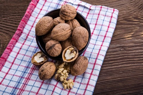 Walnut kernels and whole walnuts on old wooden table and dish towel
