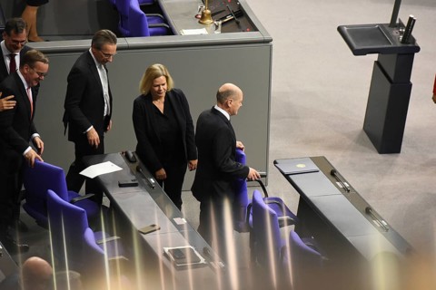Federal Chancellor Olaf Scholz (SPD) holds on to the back of his chair while some of his ministers
