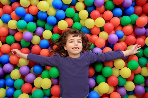 Colorful balls funny park little girl lying gesturing happy