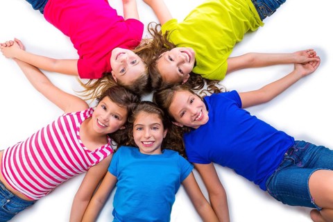 Happy kid friend girls group smiling aerial view lying on circle over white background holding