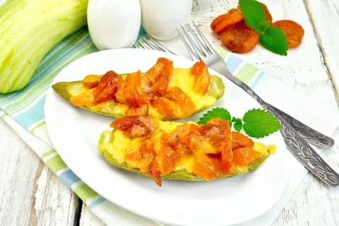 Young zucchini baked in a flavored sauce with dried apricot, cream and cheese in a bowl on a towel
