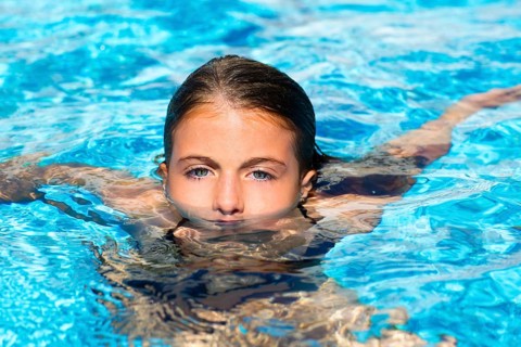 Beautiful blue eyes kid girl at the pool with face in water surface