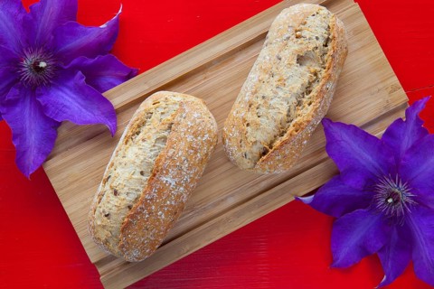 Fragrant breakfast - Two wheat bread and clematis flower on wooden desk
