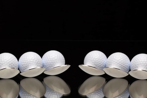 Six spoons and golf balls on a black glass desk