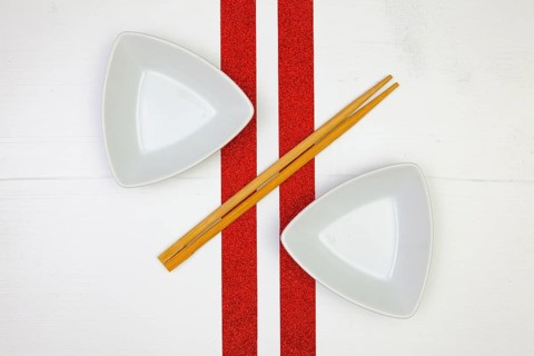 Ceramic bowls and bamboo chopsticks for sushi food with on the white wooden table.Top view. Flat