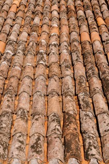 The texture of the old brown shingles on the roof of the building.
