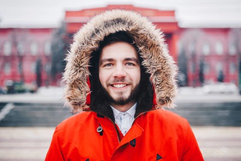 Portrait, close-up of young stylishly man smiling with a beard dressed in red winter jacket with a